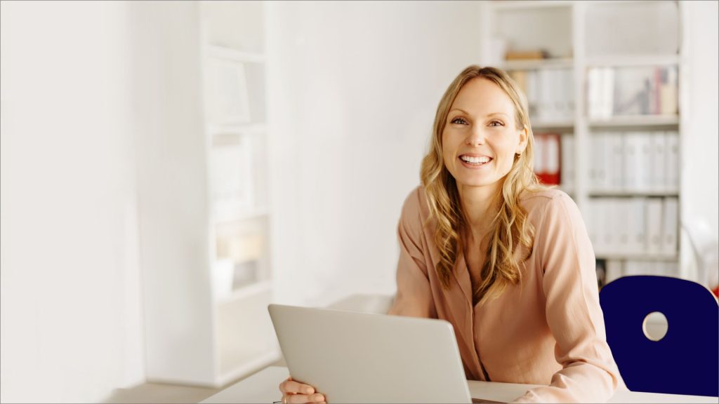 Therapist sitting at a desk with a laptop in a bright, welcoming office.